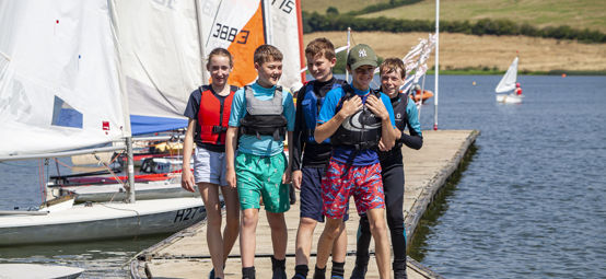 Children walking on a pontoon with dinghies in the background