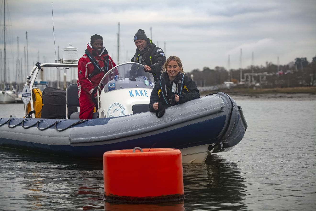 three people on a rib about to moor up to a buoy