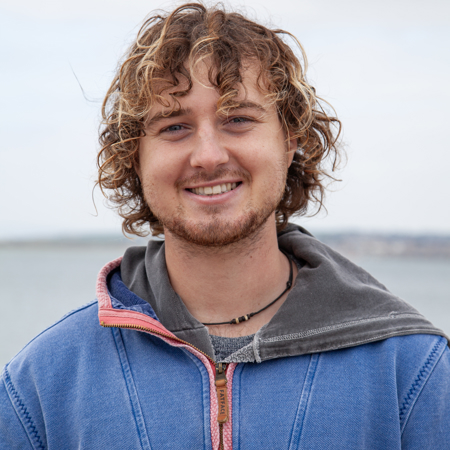 Mid shot of male sailor smiling with the sea behind him