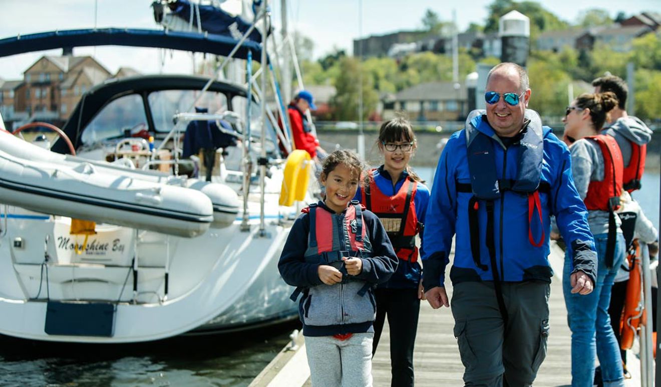 man and two young girls walking along the dock