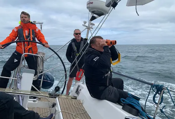 Three men sailing a Driven by Nature yacht on the open sea