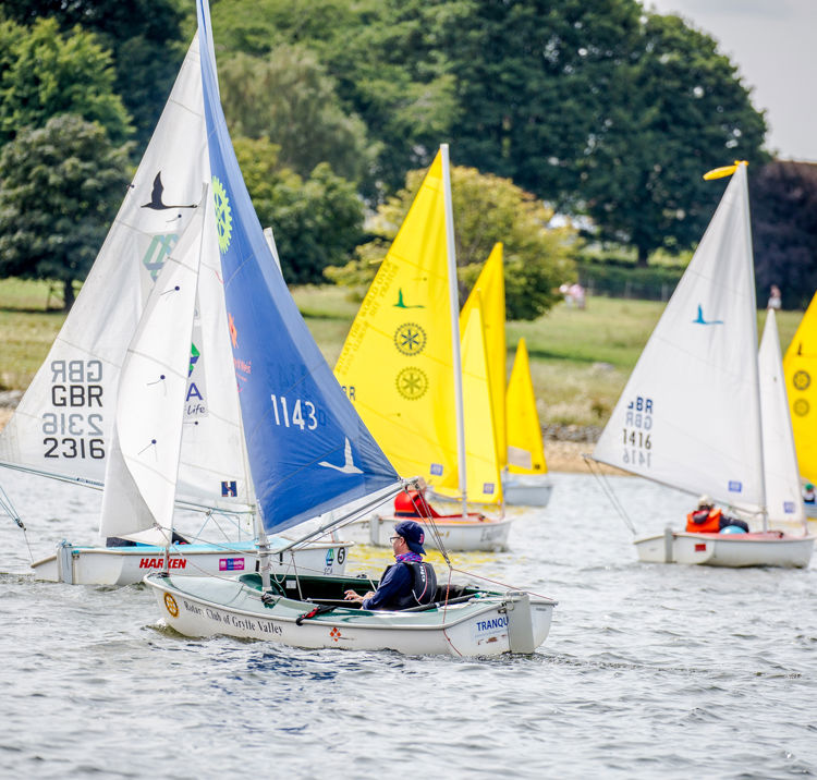 Multiple dinghies sailing across the water during a session
