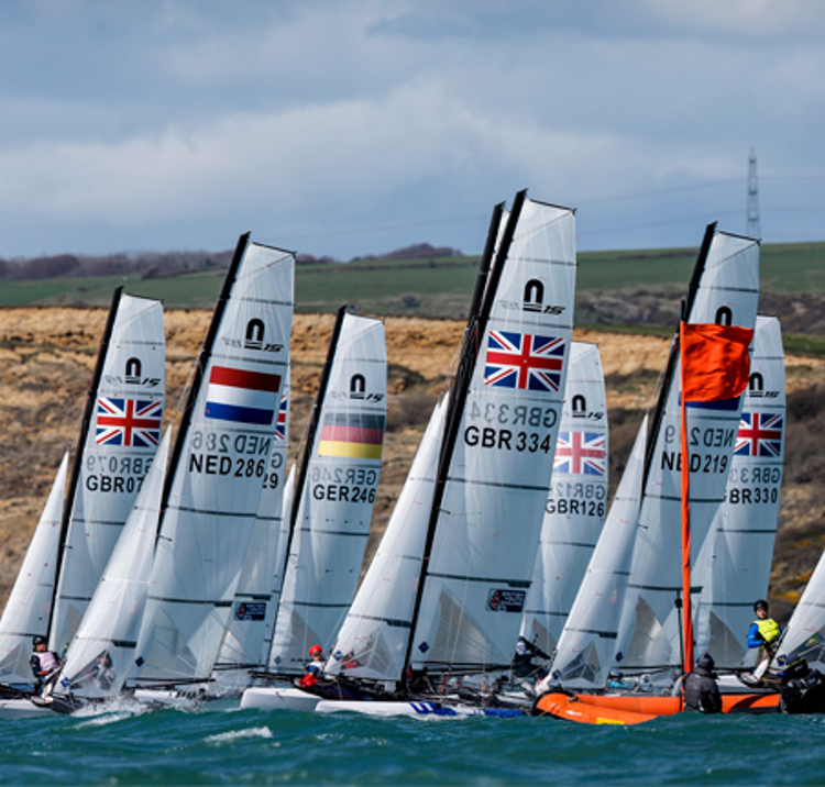	An image of boats sailing across the sea with a race officer leading the race
