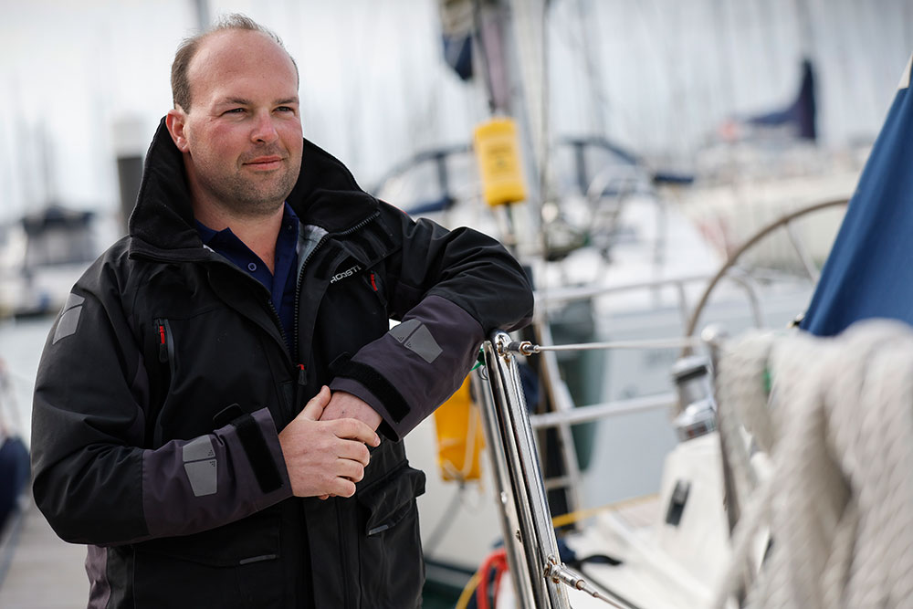 Shot of Tom stood next his boat and leaning on it 
